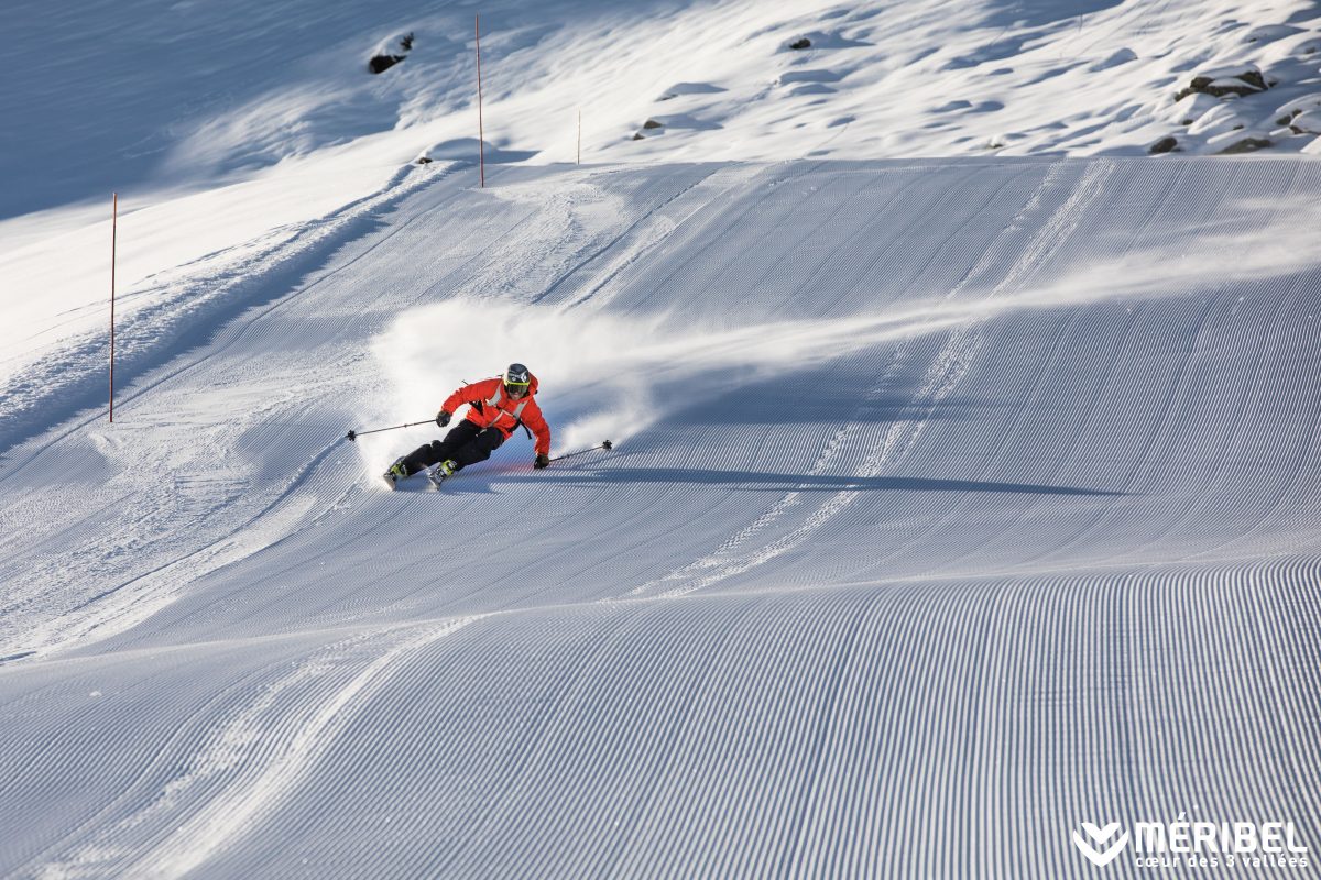 Which is better, skiing or snowboarding? Skier racing down piste in Meribel