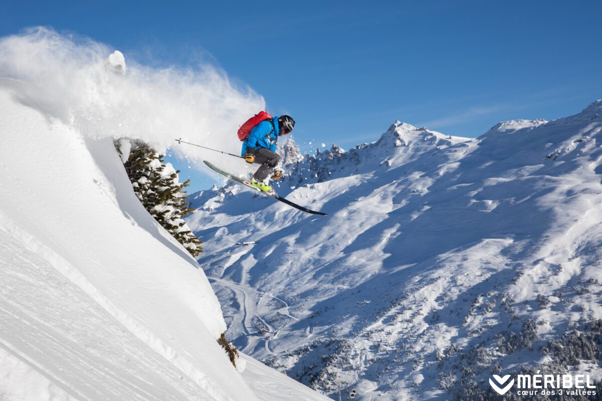 off-piste skier jumping off rock edge in meribel