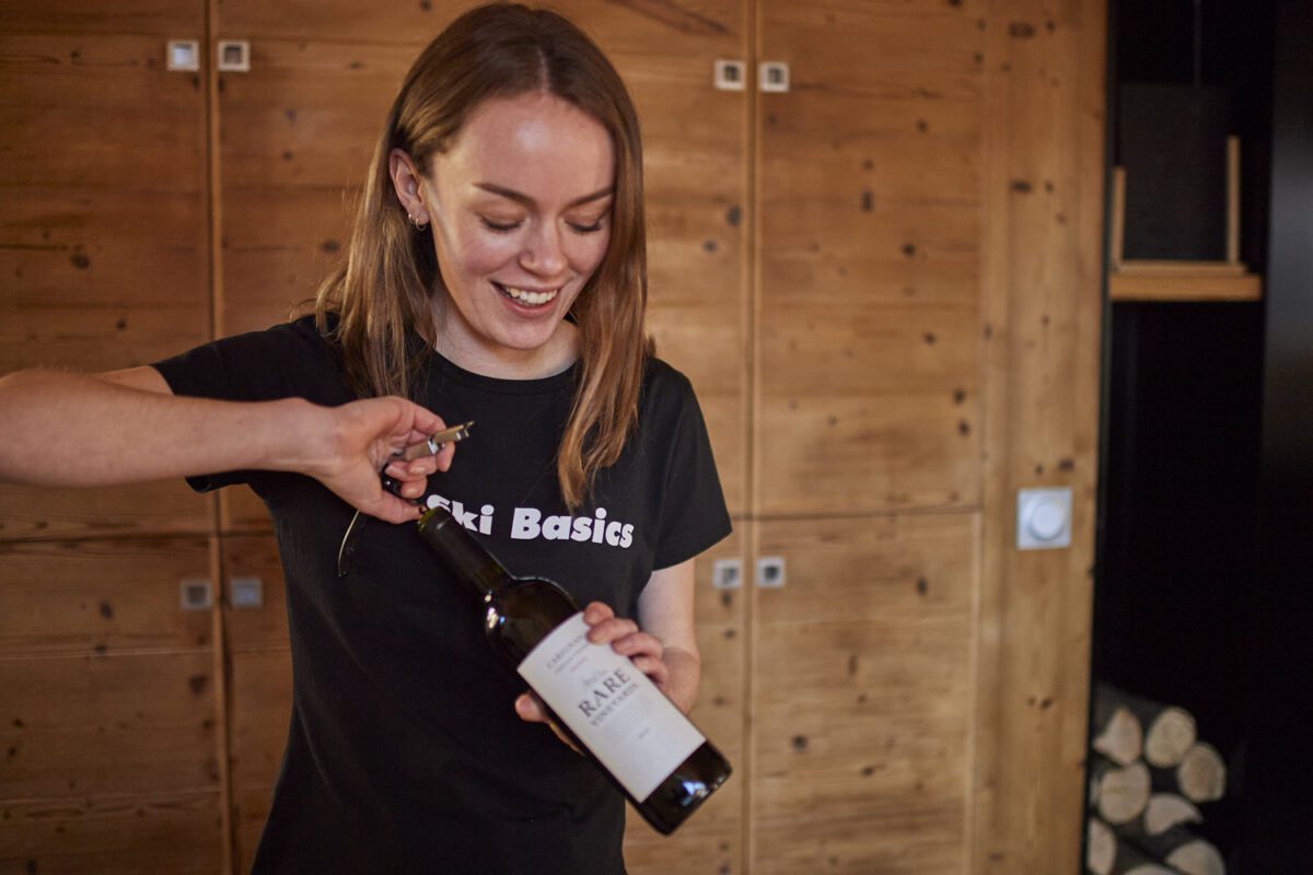 Ski Basics Chalet host opening a bottle of wine for guest in catered ski chalet in Meribel Village